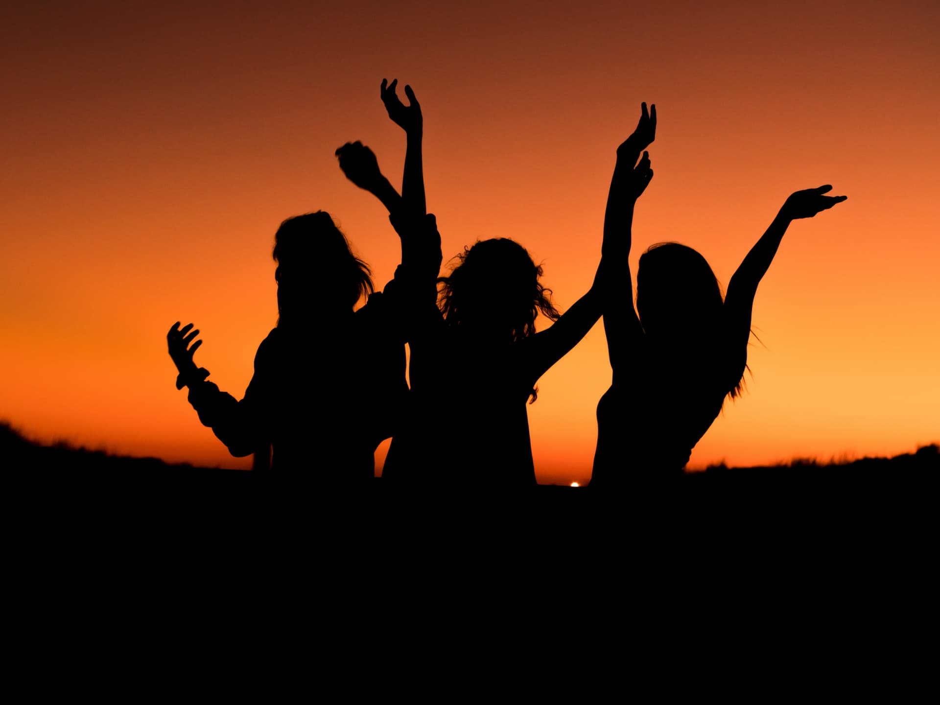 Drei Frauen tanzen unter dem Abendhimmel