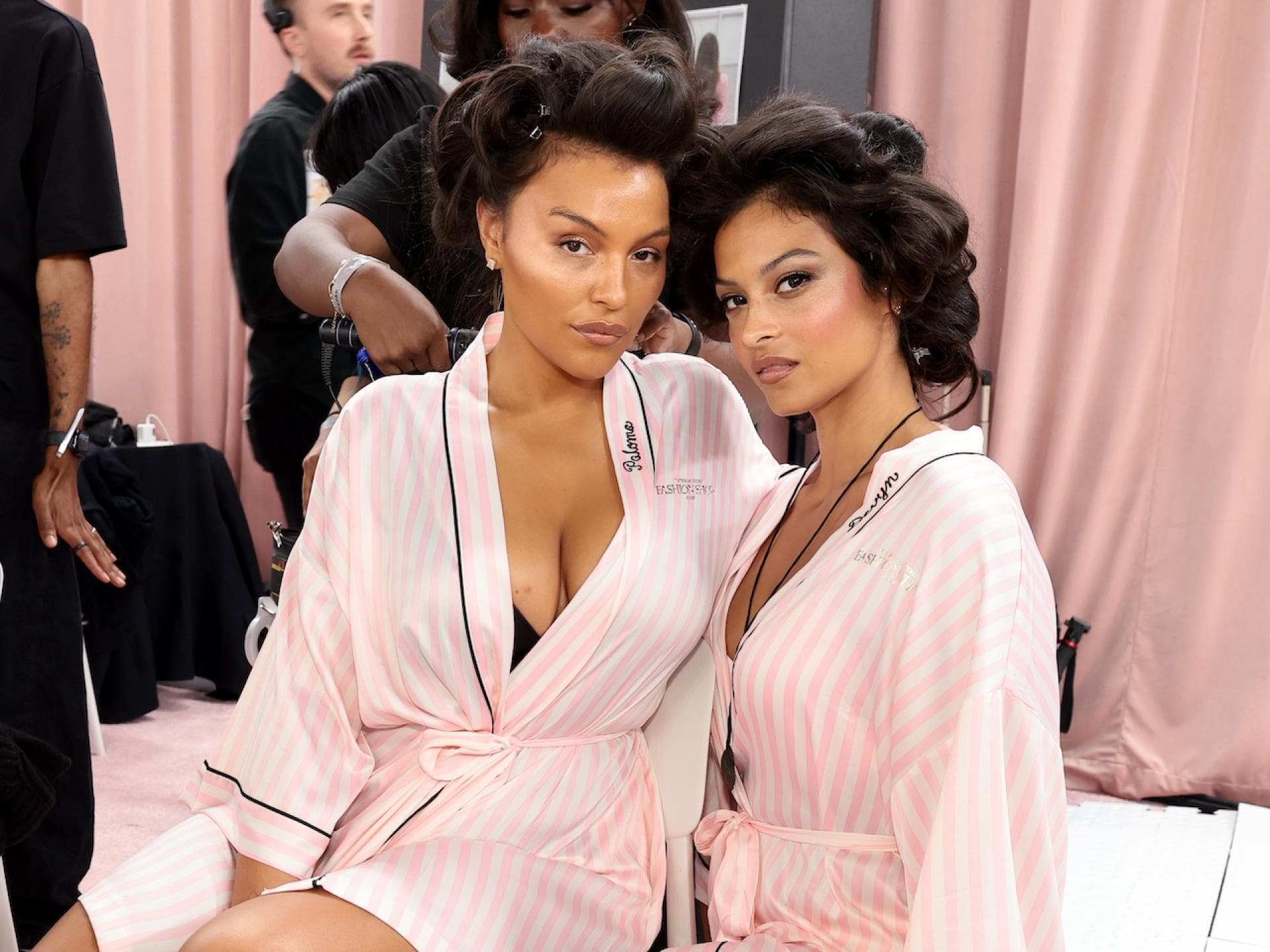 Für Bombshell Curls müssen die Haare in Lockenwickler gewickelt werden. Zwei Models mit rosafarbenen Bademäntel und eingewickelten Haaren.