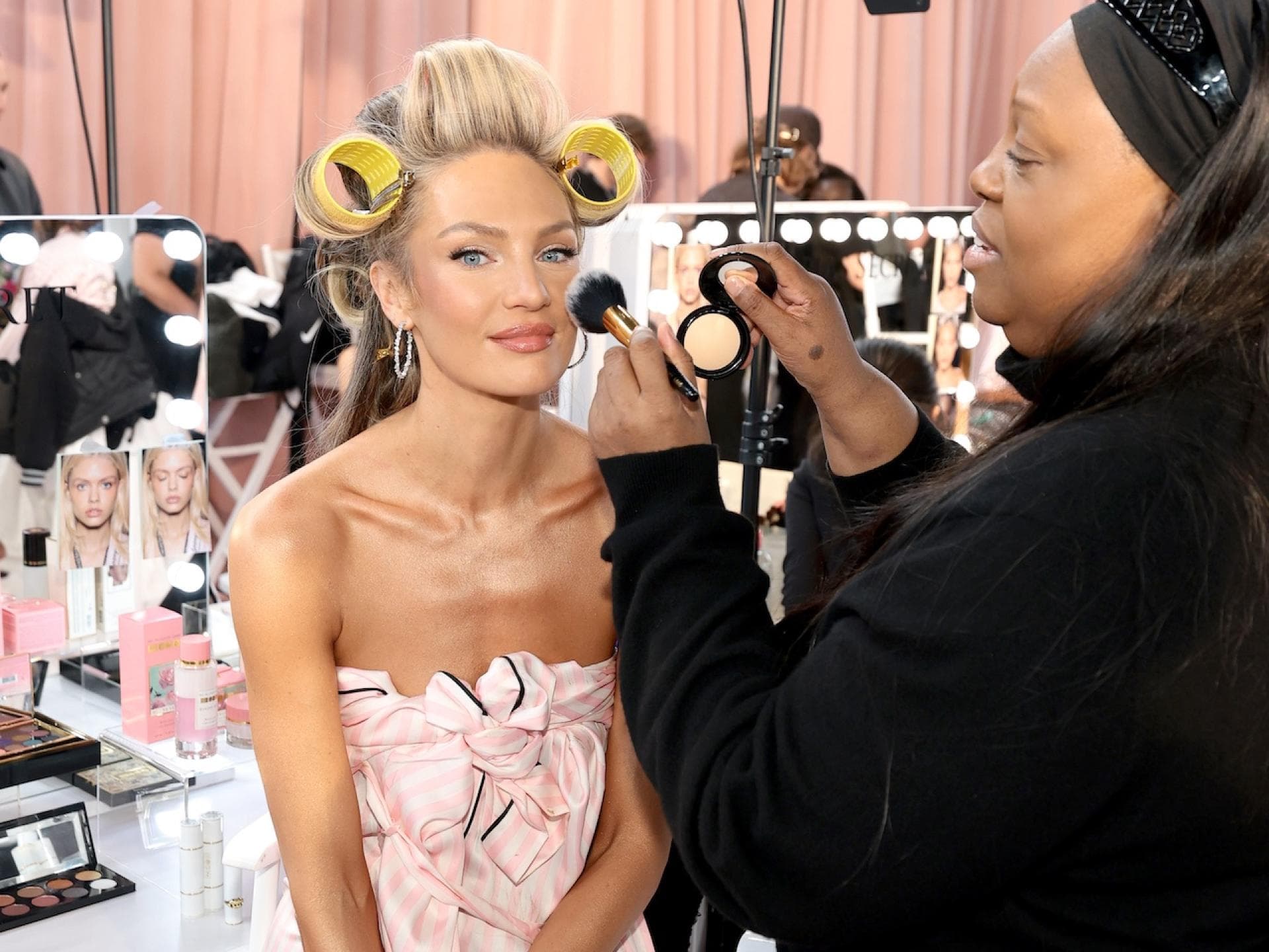 Candice Swanepoel wird Backstage wie ein Engel behandelt. Candice Swanepoel wird geschminkt und hat Lockenwickler im Haar.