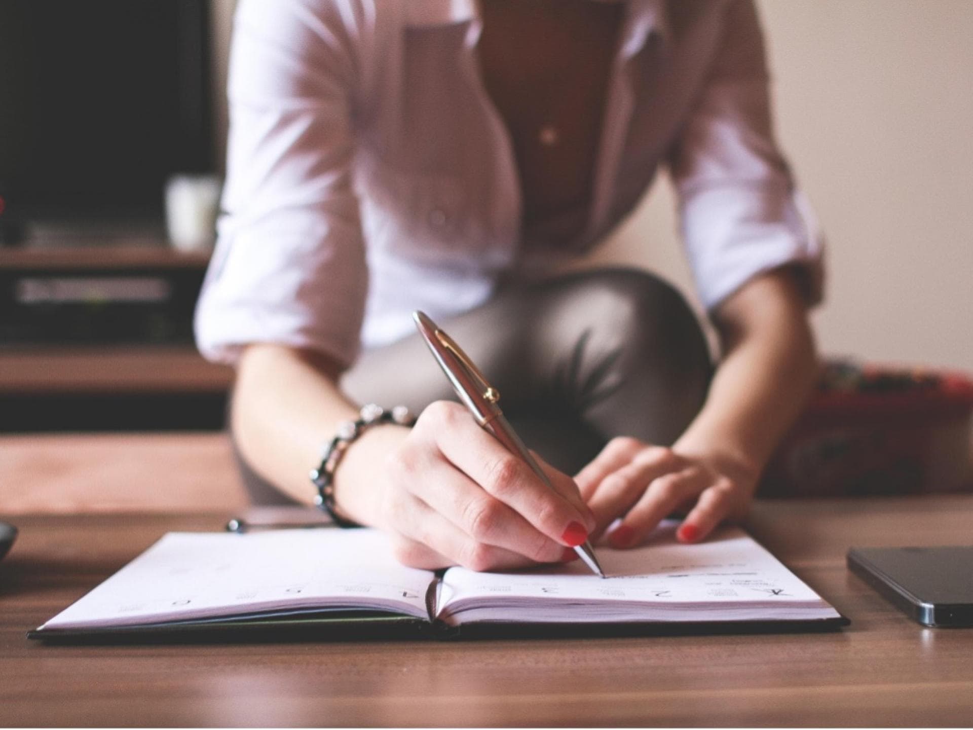 Eine Frau schreibt in ihr Notizbuch