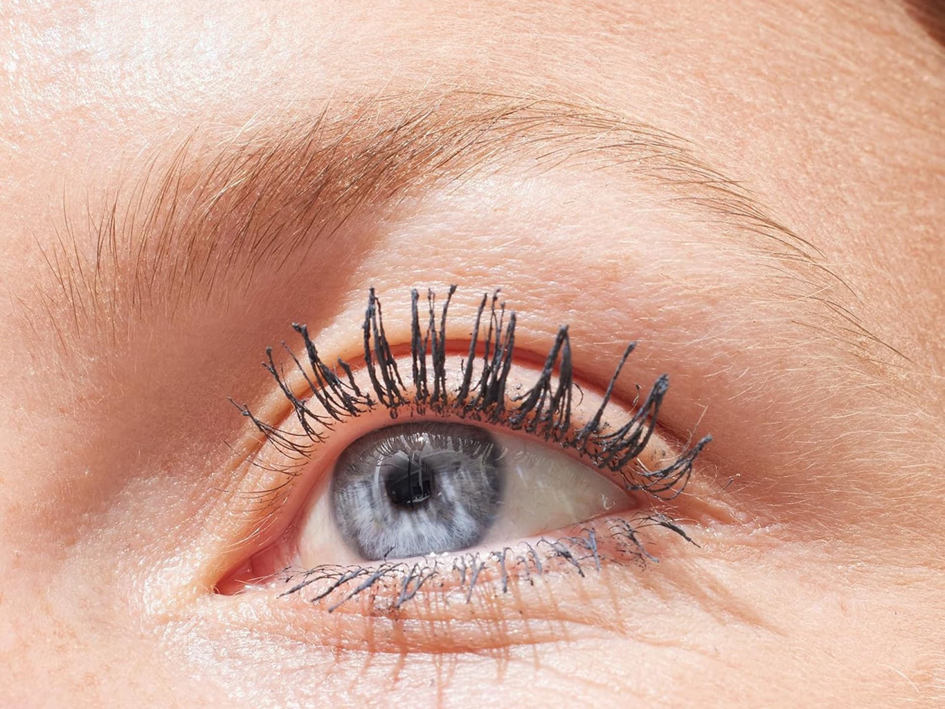 Graue Mascara ersetzt jetzt den schwarzen Klassiker. Nahaufnahme Auge mit grauer Mascara