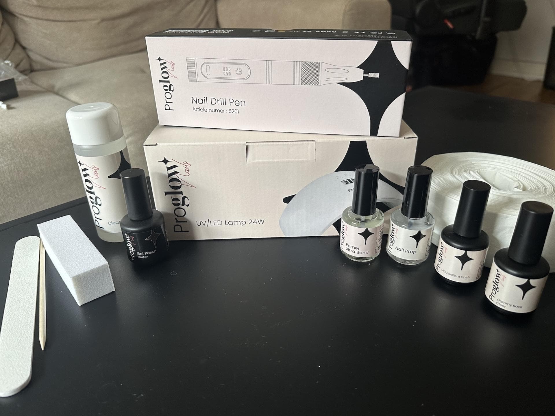 Mit dem Starter Set von Proglow gelingt die Maniküre zuhause ganz einfach. Starter Set von Proglow auf einem schwarzen Couchtisch.