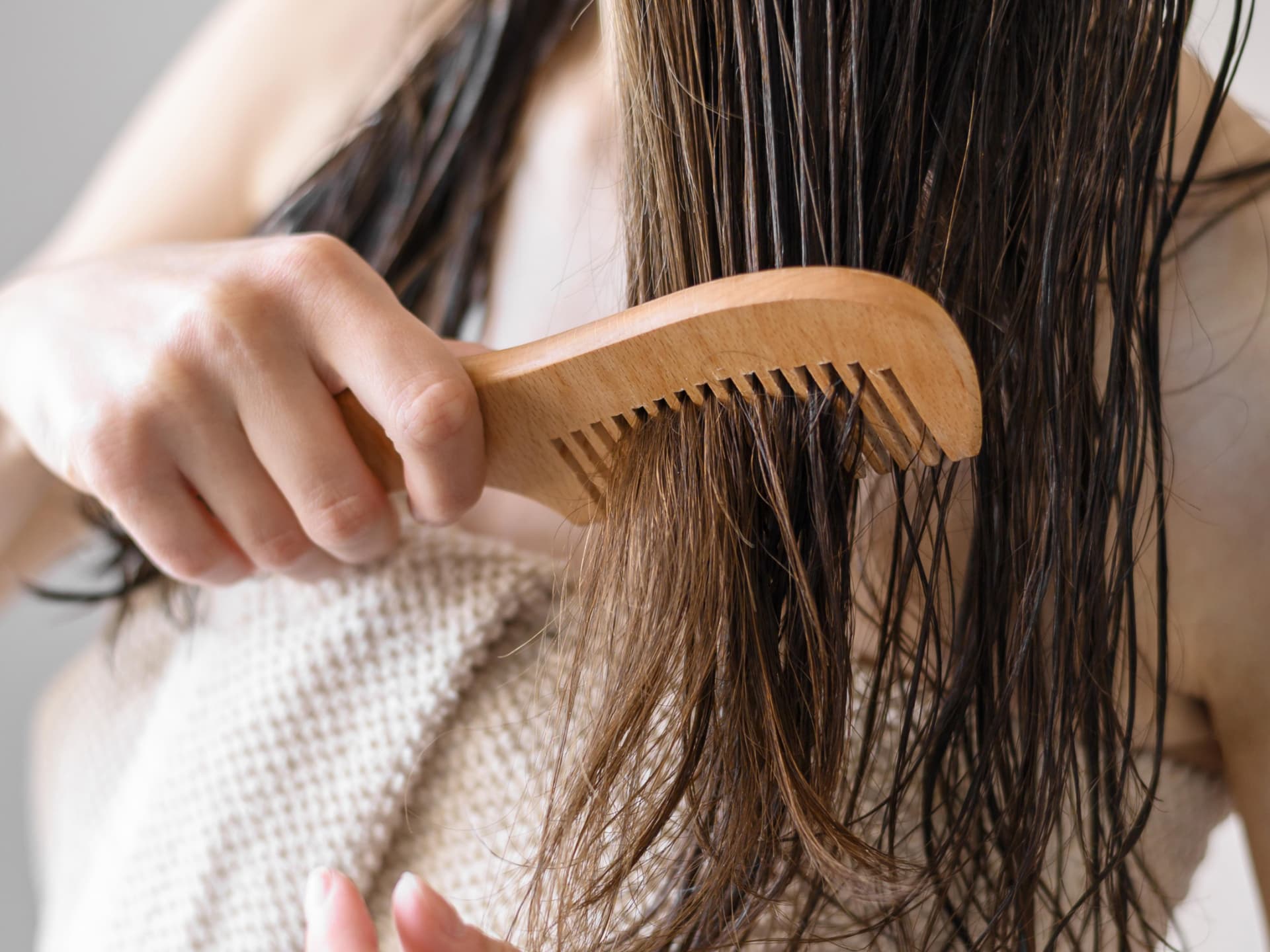 Wie du dein Low Porosity Hair richtig pflegst, verrate ich dir hier. Frau kämmt nasses Haar
