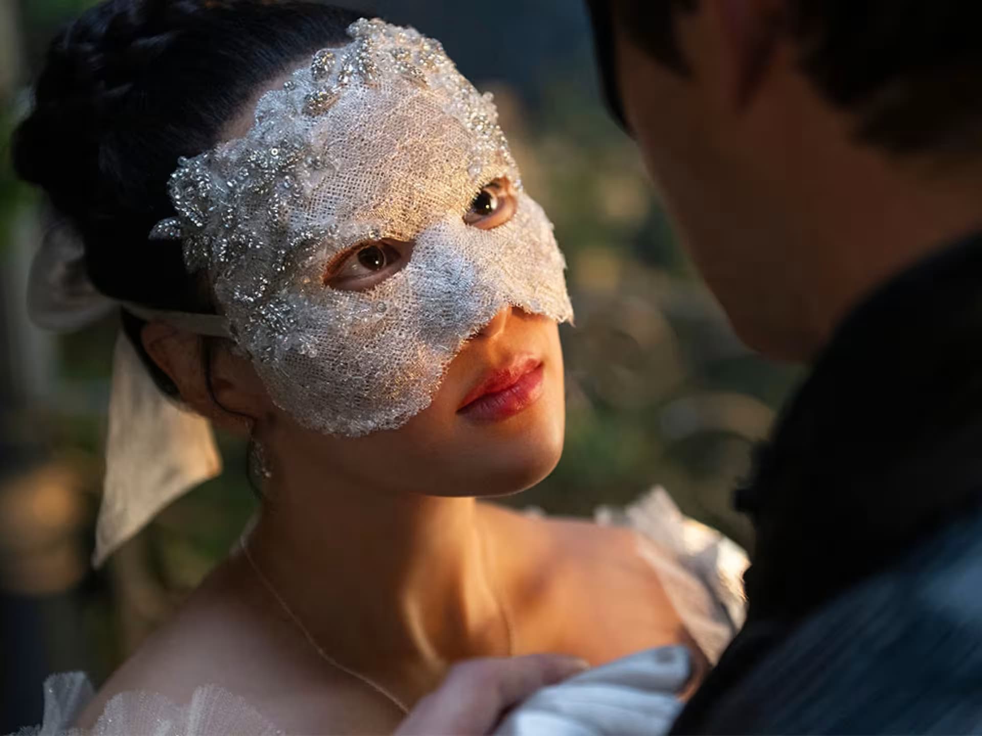 Sophie spielt in „Bridgerton“ Staffel 4 die „Lady in Silver“. Eine junge Frau mit einer Maske schaut einen Mann an.