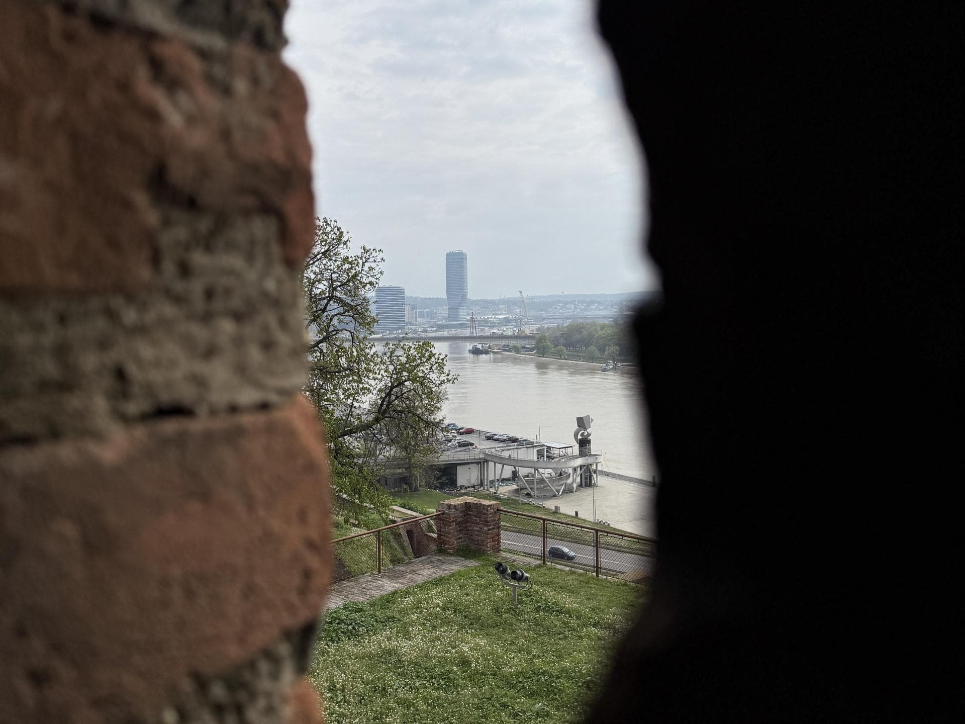 Ein Blick durch einen Mauerspalt auf einen Fluss und die Waterfront in Belgrad.
