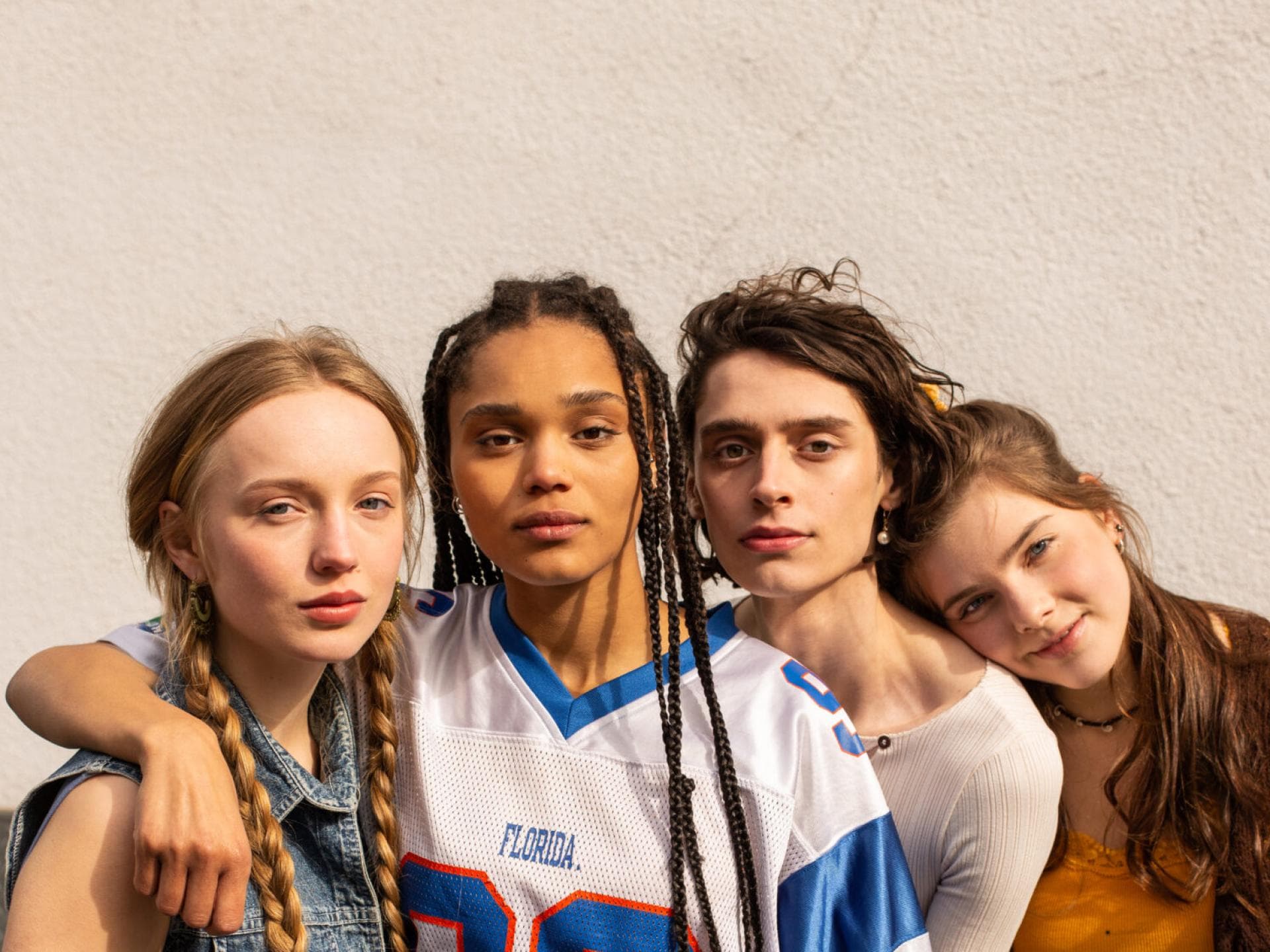 Vier Teenager stehen eng beieinander und gucken in die Kamera.