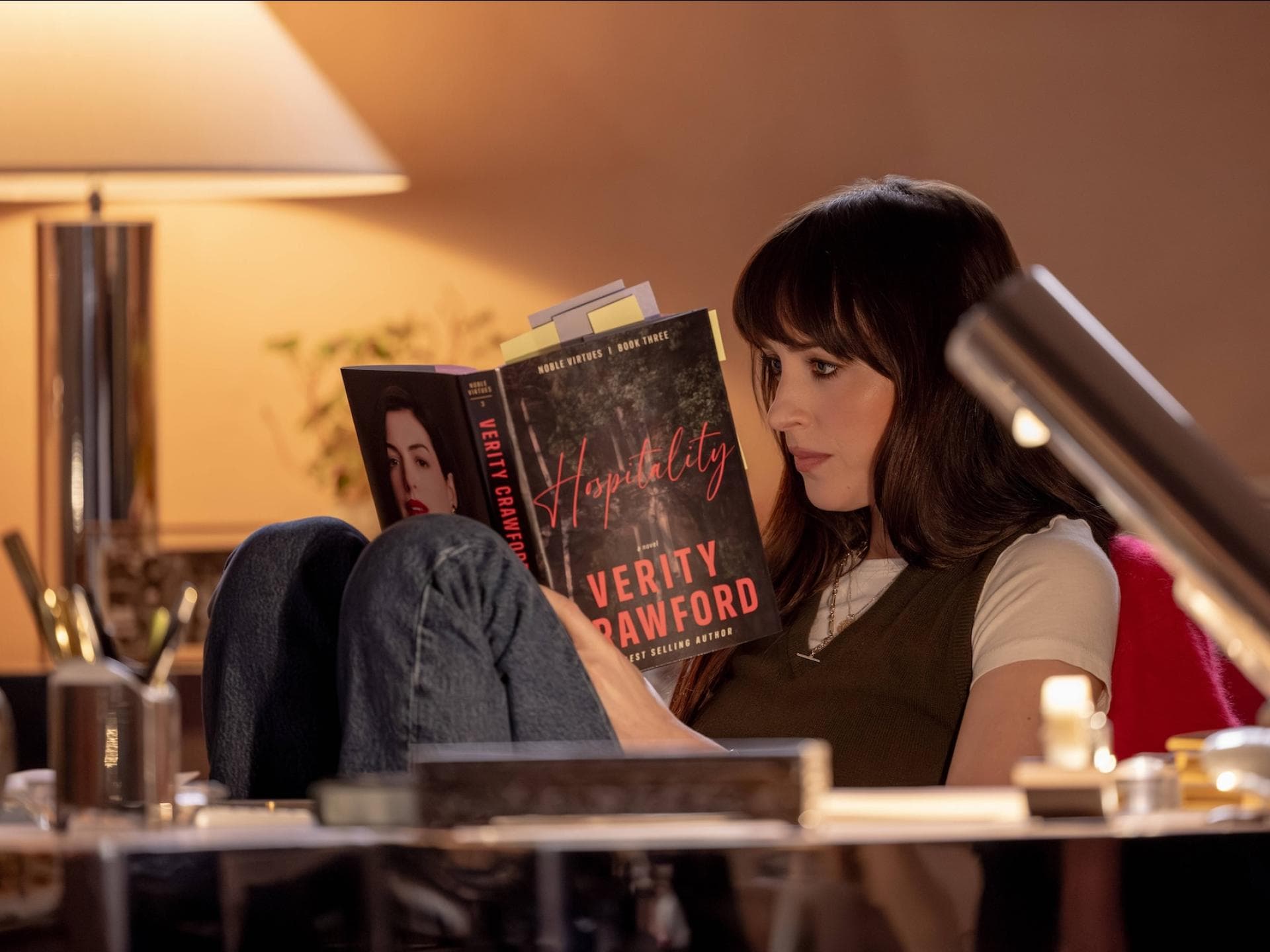 Dakotha Johnson sitzt in einem Zimmer mit gedämmtem Licht und liest ein Buch.