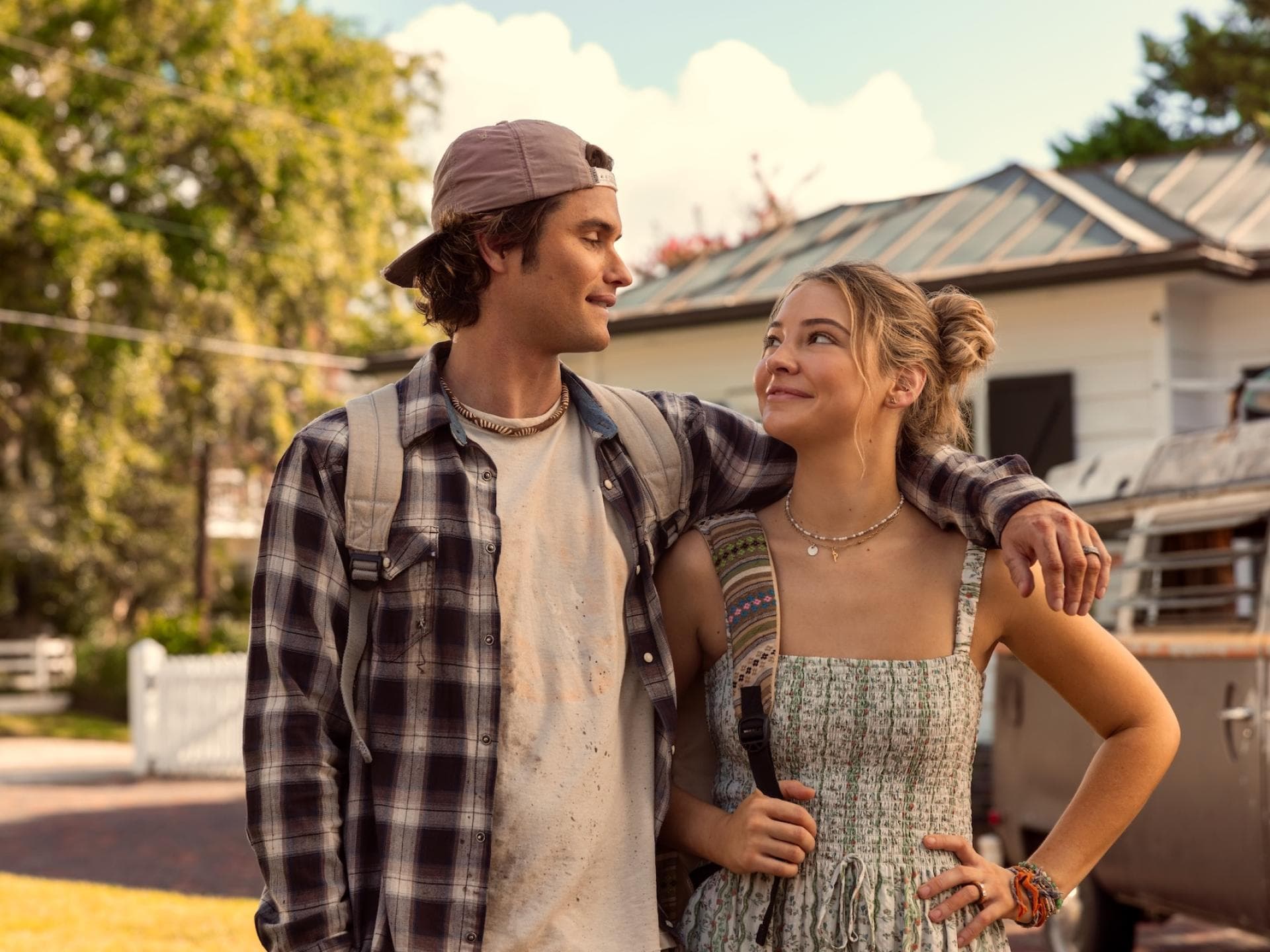In Staffel 5 sind wir gespannt, wie es mit John B und Sarah und ihrem Baby weitergeht. Eine junger Mann mit Cap und Hemd legt seinen Arm um eine junge Frau im Kleid und beide gucken sich an.
