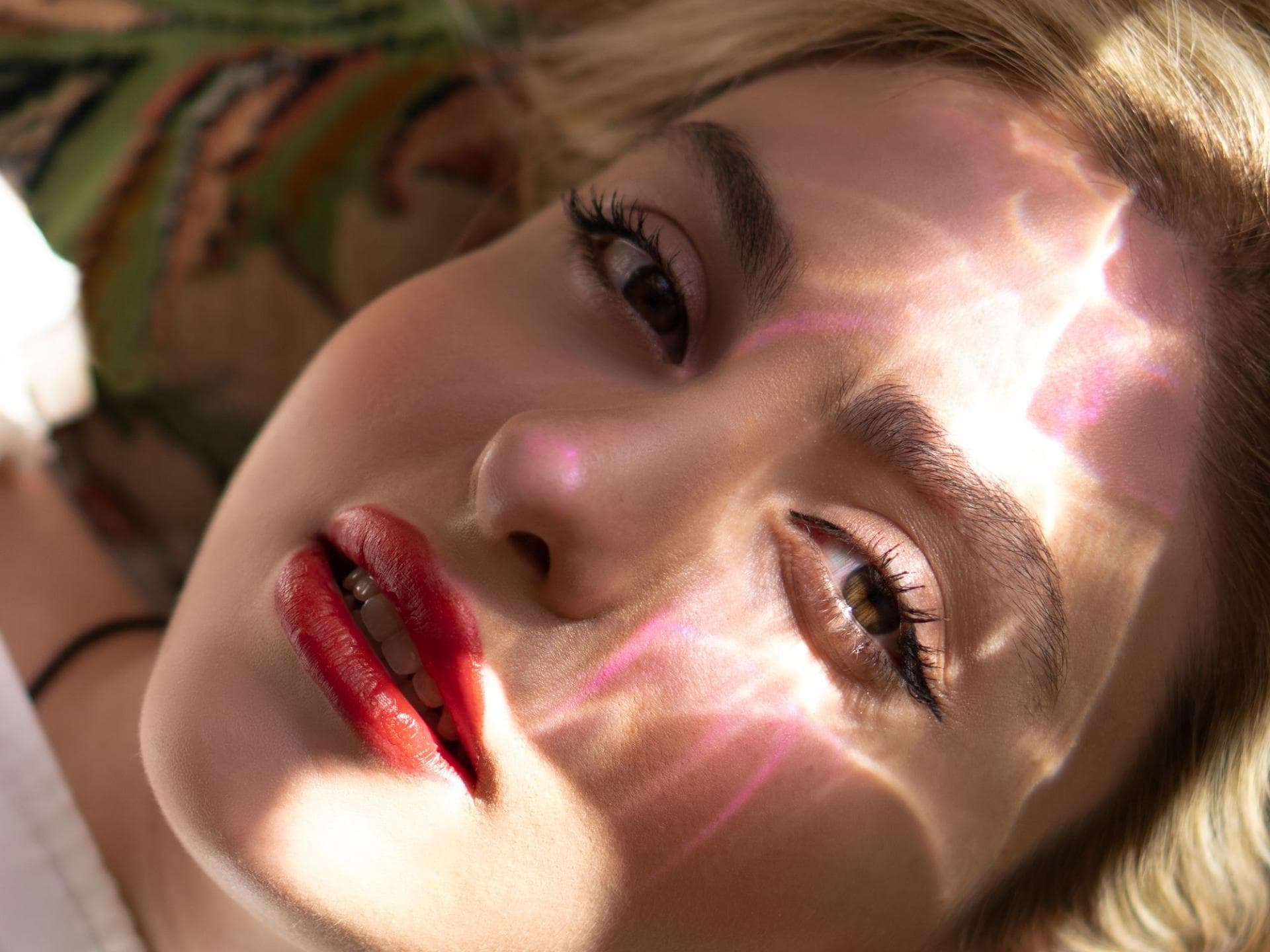 Frau mit glänzendem Lippenstift und Sonne im Gesicht Frau mit glänzendem Lippenstift und Sonne im Gesicht