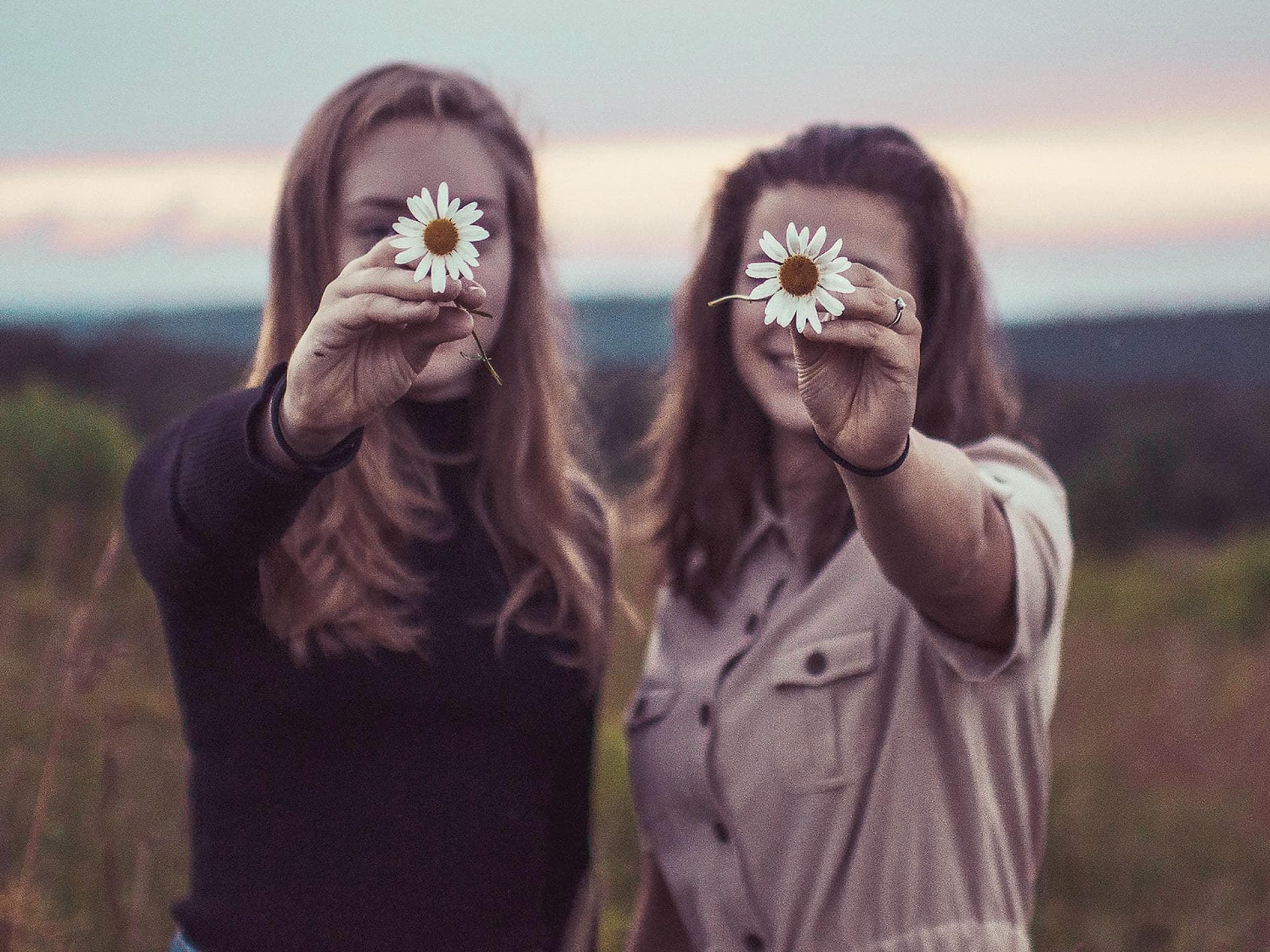 Blogartikel: Diese Sternzeichen sind die besten Freunde Zwei Frauen halten Blumen vor ihr Gesicht