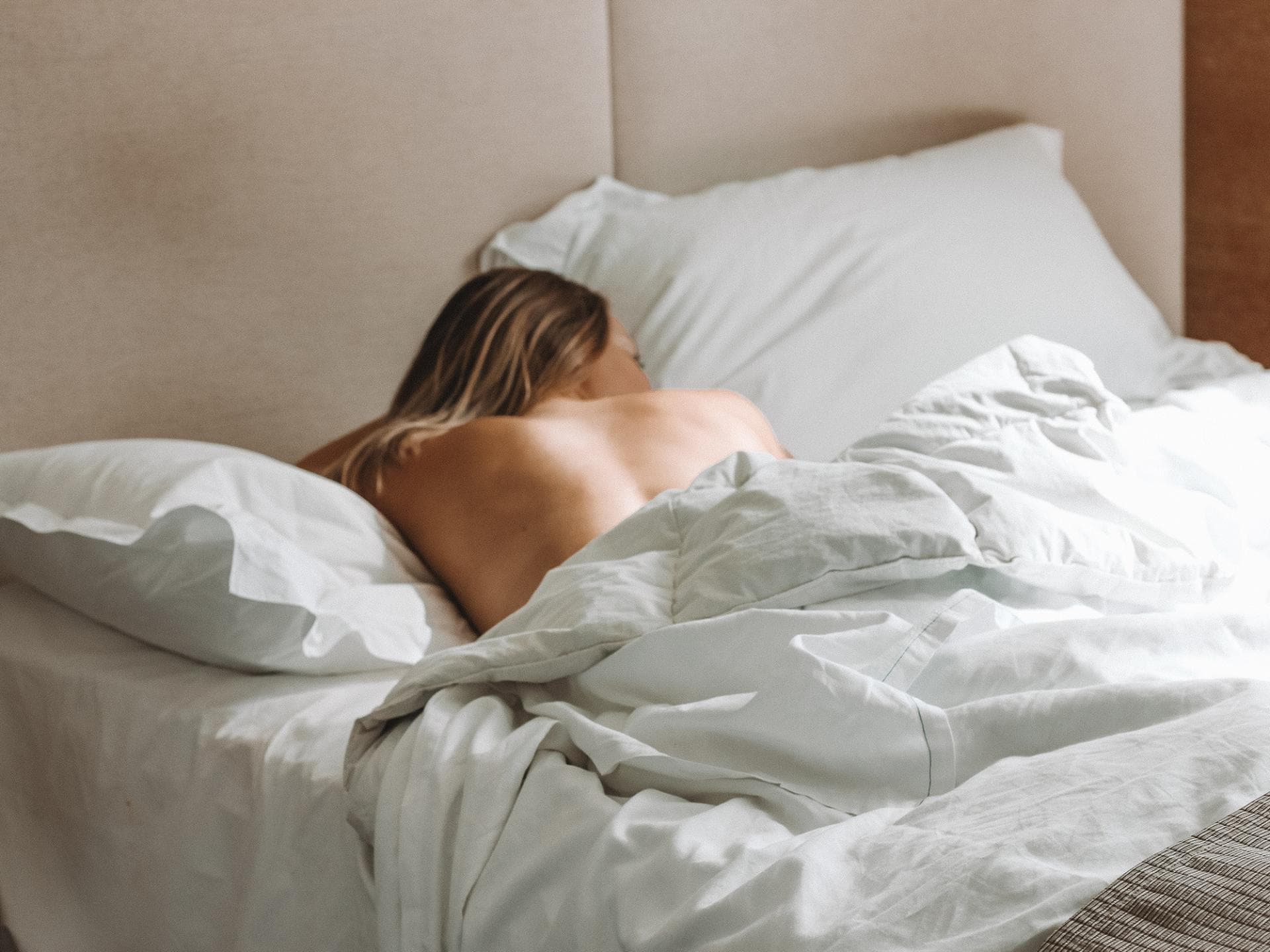 5 Tipps, um bei Hitze erholsam zu schlafen Frau liegt unbekleidet im Bett