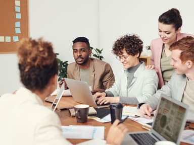 Frauen und Männer sitzen am Arbeits-Tisch