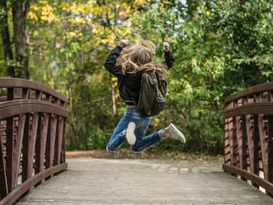 Frau springt auf einer Brücke hoch
