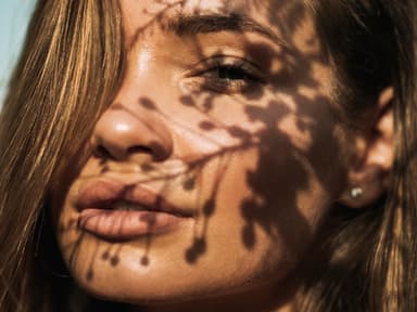Frau scheint Sonne ins Gesicht