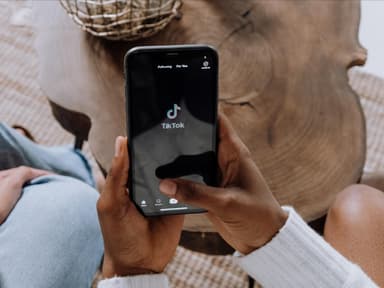 Frau hält Handy mit TikTok App hoch