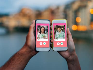 Hand von Mann und Frau mit Smartphone jeweils in der Hand, auf welchem Tinder geöffnet ist