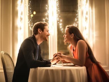 Valentinstag Date: Mann und Frau sitzen an einem Tisch der mit Lichterketten geschmückt ist