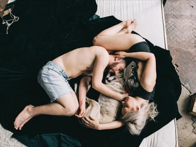 On-Off-Beziehung: Mann und Frau liegen mit Hund auf einem Bett 