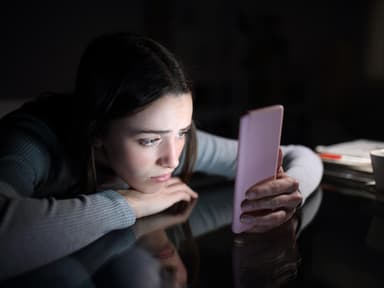 Frau guckt traurig auf ihr Smartphone