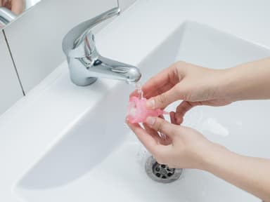 Menstruationstasse unter Wasserhahn reinigen