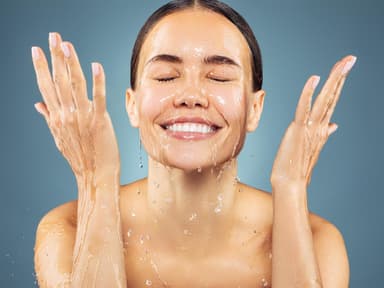 Frau wäscht sich mit Wasser das Gesicht 
