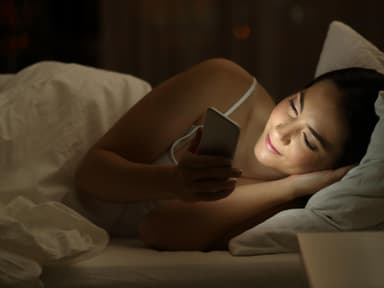 Sexting: Frau mit Handy im Bett