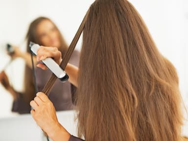 Frau glättet sich Haare