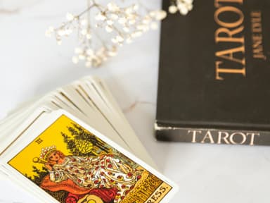 Tarot karten und ein Tarot Buch liegen auf einem Tisch