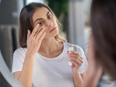 Frau deckt Augenringe mit Concealer ab