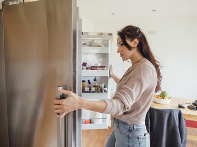Frau schaut in den Kühlschrank