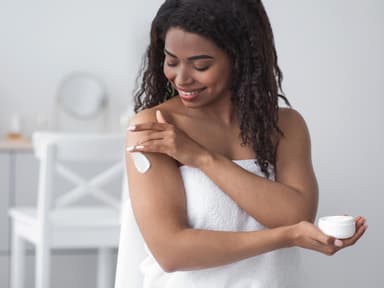 Frau trägt Bodylotion auf