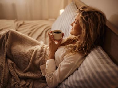 Junge Frau trink Tee im Bett 