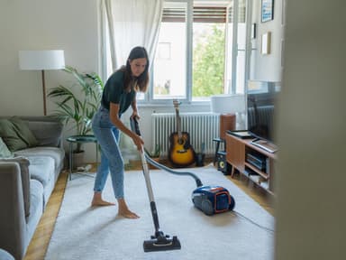 Frau saugt das Wohnzimmer