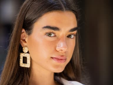 Frau mit Sommerteint und braunen offenen Haaren sowie großen Ohrringen.