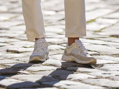 Frau trägt beige-weiße Sneaker mit Plateau-Sohle