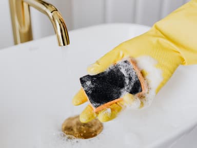 Gelber Handschuh mit Schwamm im Waschbecken