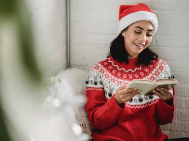 Frau im Weihnachtspullover liest ein Buch