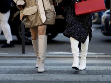 Zwei Frauen tragen auf Paris Fashion Week kniehohe Stiefel mit Absatz