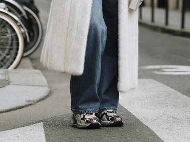 Frau trägt auf Paris Fashion Week weißen Fake Fur Mantel Jeans und Sneaker