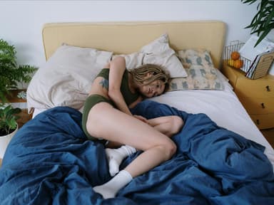 Frau liegt mit Schmerzen im Bett