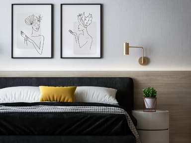Schalfzimmer mit Bett, Nachttisch und Bildern an der Wand