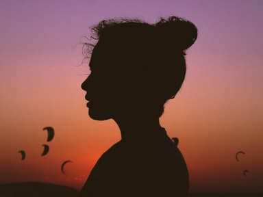 Frau mit Dutt steht vor einem Sonnenuntergang