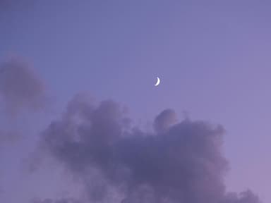 Halbmond am lilafarbenen Himmel mit Wolken