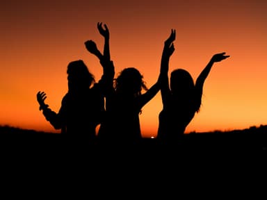Drei Silhouetten von Frauen vor Sonnenuntergang