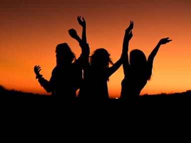 Drei Frauen tanzen unter dem Abendhimmel