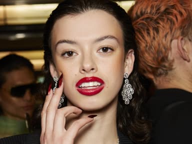 Frau mit roten Lippen, großen Ohrringen und roten Nägeln.