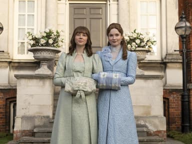 Zwei Frauen mit langen, eleganten Kleidern vor einem Schloss.