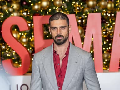 Michele Morrone in einem grauen Anzug mit rotem Hemd darunter.