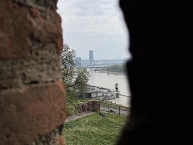 Ein Blick durch einen Mauerspalt auf einen Fluss und die Waterfront in Belgrad.