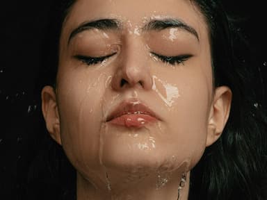 Einer Frau mit geschlossenen Augen läuft Wasser über das komplette Gesicht.